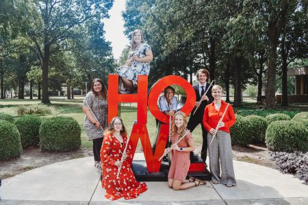 Flute studio standing in front of the Howl sculpture on the Jonesboro campus.